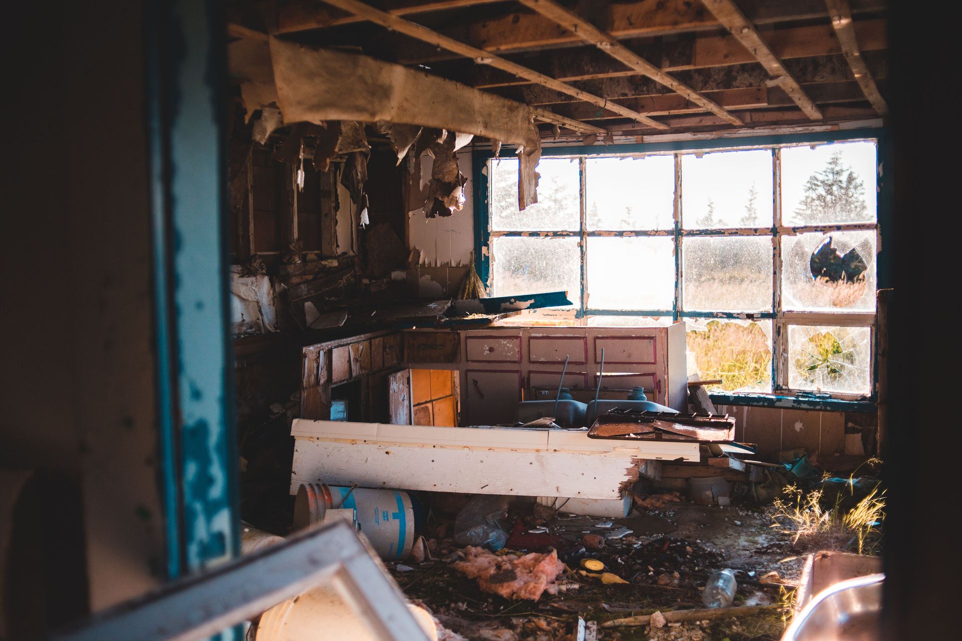 Interior of abandoned ruined building with broken window and damaged furniture with trash on floor in daylight in countryside inside